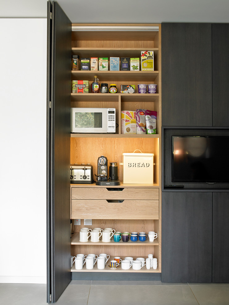 Design ideas for a contemporary kitchen pantry in London with flat-panel cabinets, black cabinets and porcelain floors.