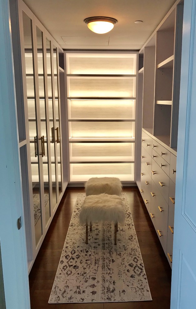 This is an example of a small contemporary gender-neutral walk-in wardrobe in Toronto with flat-panel cabinets, white cabinets and dark hardwood floors.