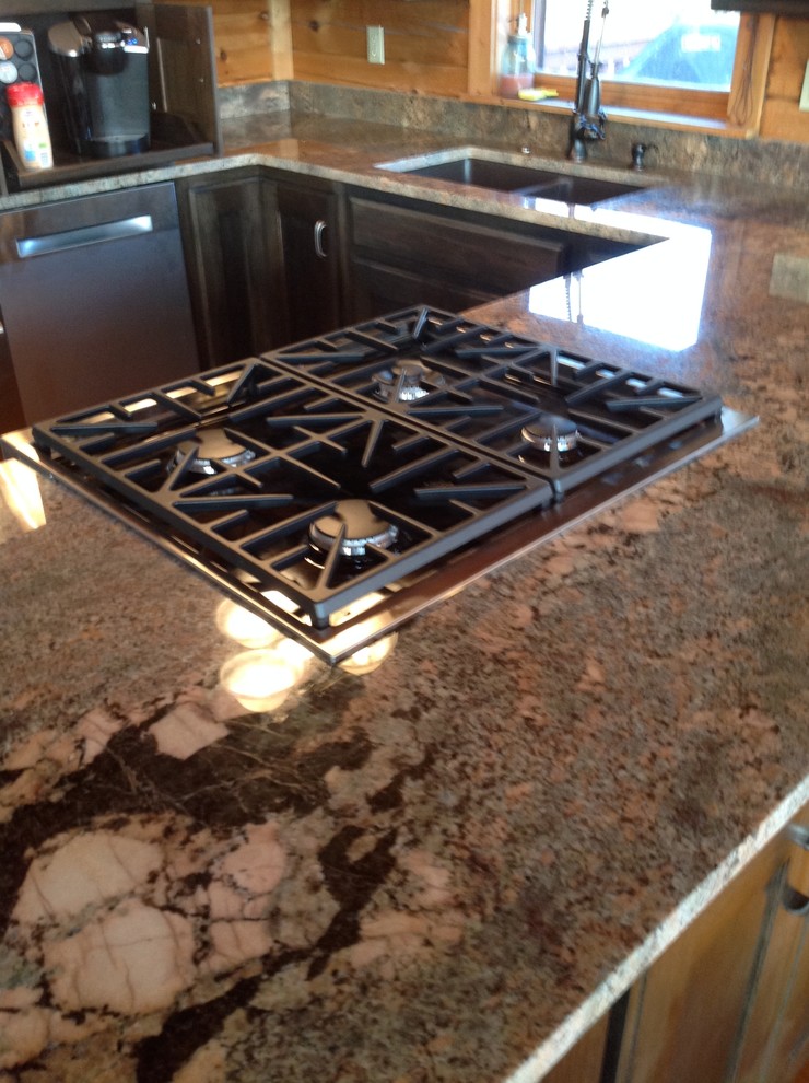 Example of a small mountain style kitchen design with a double-bowl sink, dark wood cabinets, granite countertops, stainless steel appliances and an island