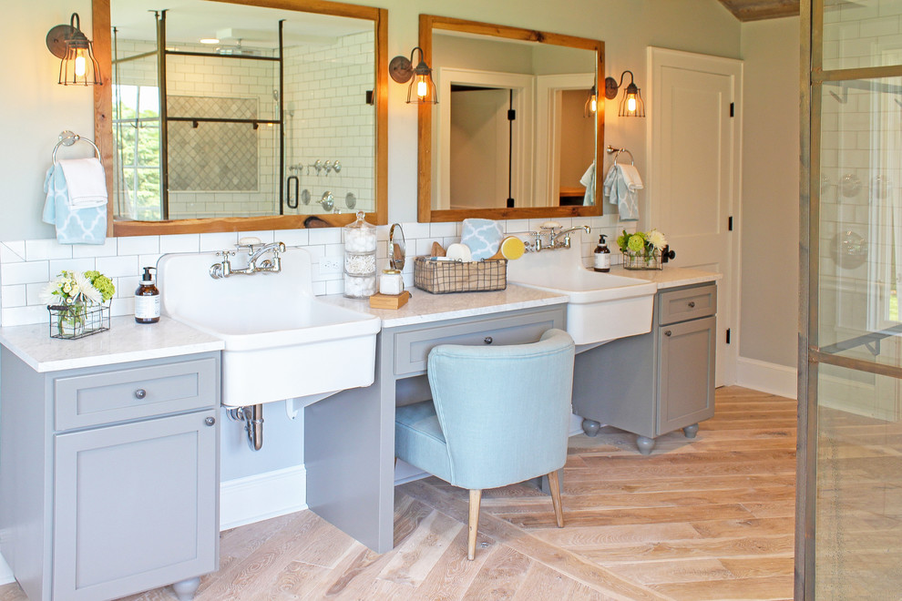 Photo of a large country master bathroom in Minneapolis with shaker cabinets, grey cabinets, a freestanding tub, a corner shower, gray tile, stone tile, grey walls, light hardwood floors, a drop-in sink and marble benchtops.