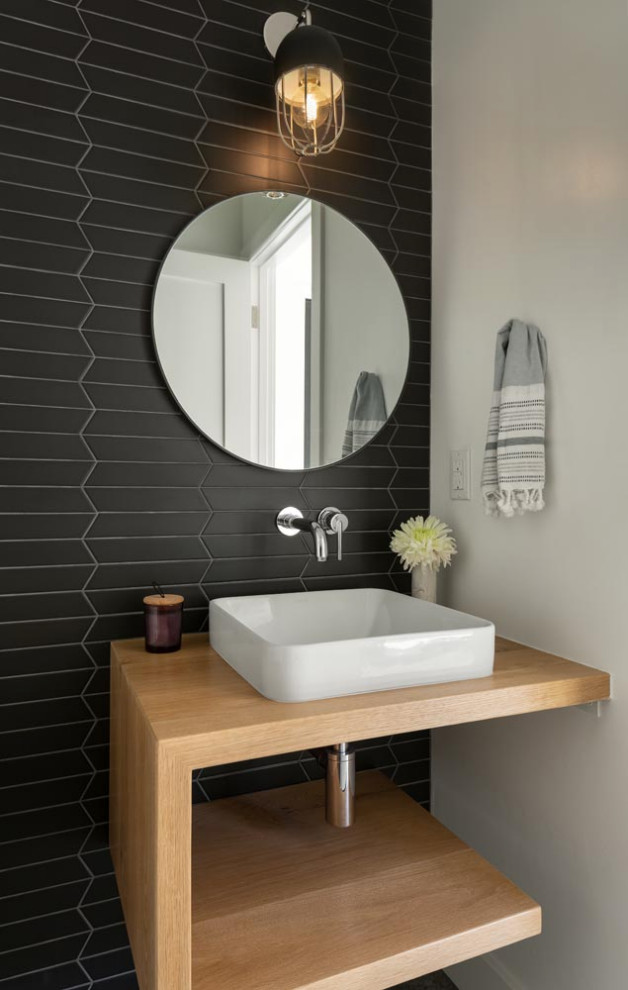 Réalisation d'un WC et toilettes nordique en bois clair avec un placard sans porte, un mur noir, sol en béton ciré, un sol gris et meuble-lavabo suspendu.