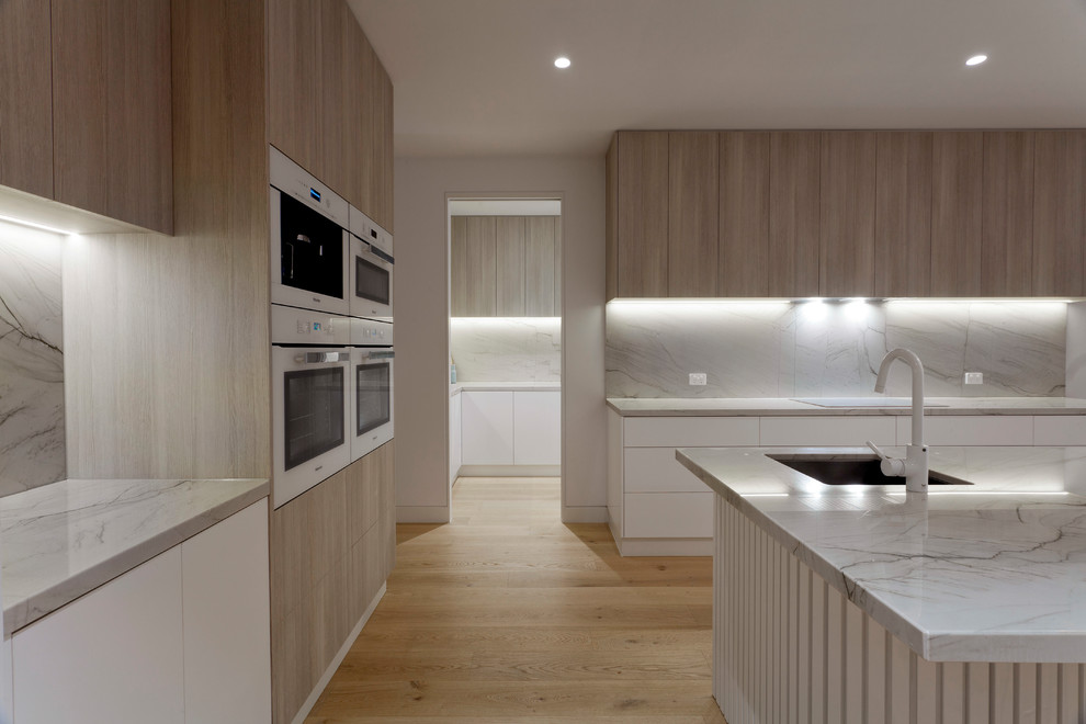 Design ideas for a large modern kitchen pantry in Melbourne with flat-panel cabinets, distressed cabinets, quartzite benchtops, white appliances and with island.