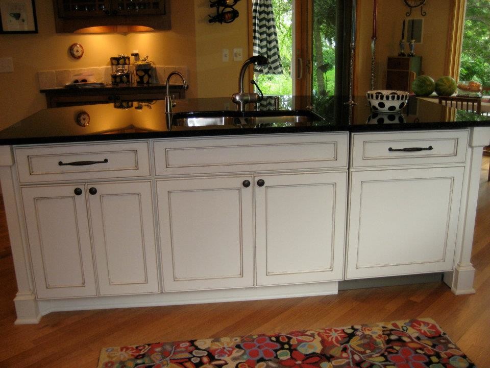 Example of a mid-sized transitional l-shaped dark wood floor open concept kitchen design in Milwaukee with a double-bowl sink, recessed-panel cabinets, white cabinets, beige backsplash, stone tile backsplash, stainless steel appliances, an island and granite countertops
