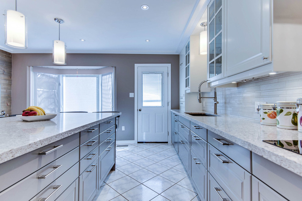 Mid-sized transitional l-shaped separate kitchen in Toronto with an undermount sink, raised-panel cabinets, white cabinets, quartz benchtops, beige splashback, porcelain splashback, stainless steel appliances, ceramic floors and with island.