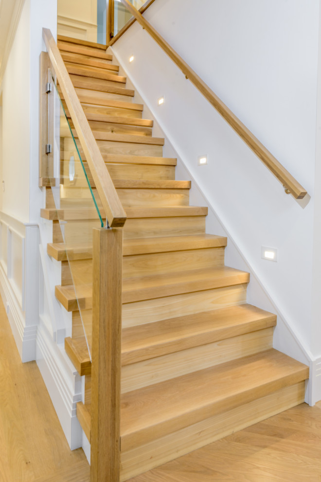 This is an example of a large contemporary wood straight staircase in New York with wood risers and wood railing.