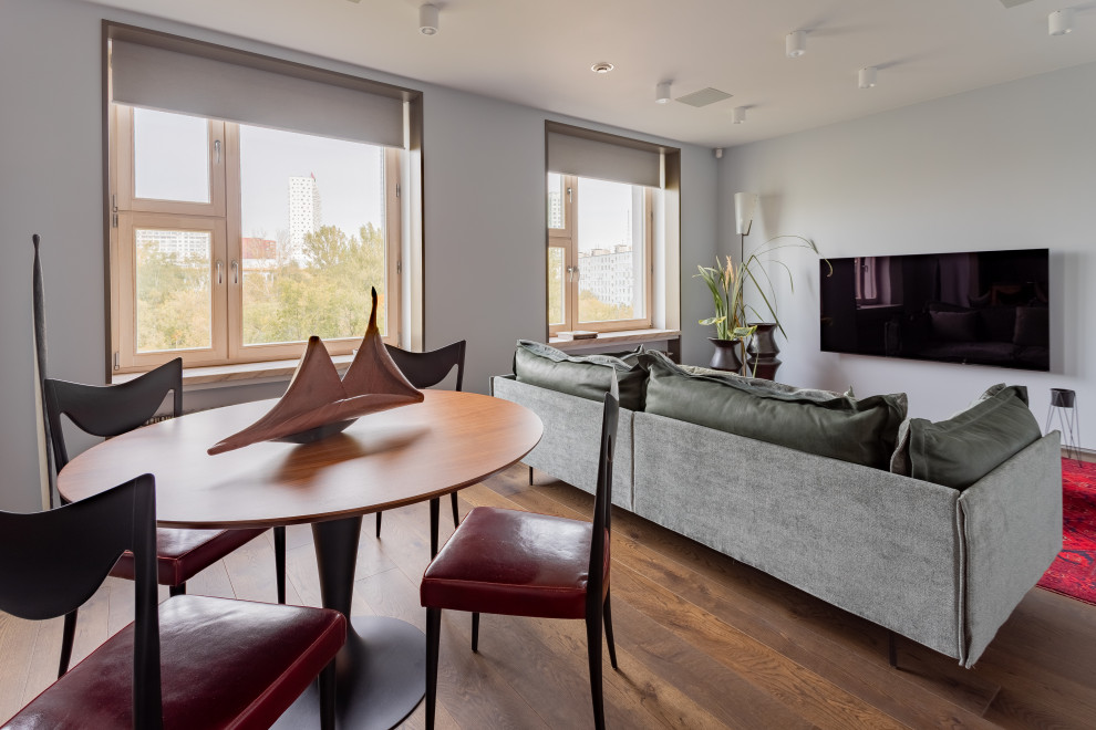 Immagine di un soggiorno contemporaneo di medie dimensioni con pareti grigie, pavimento in legno massello medio, TV a parete e pavimento marrone