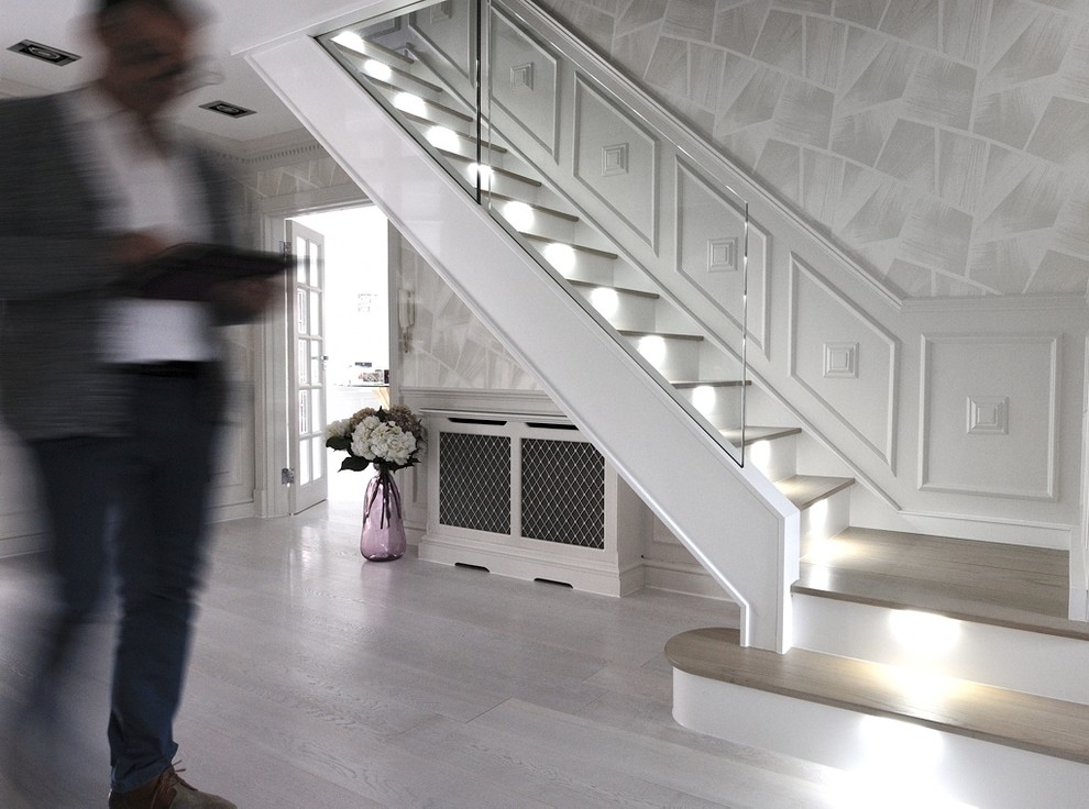 Inspiration for a large contemporary wood curved staircase in London with glass risers and glass railing.