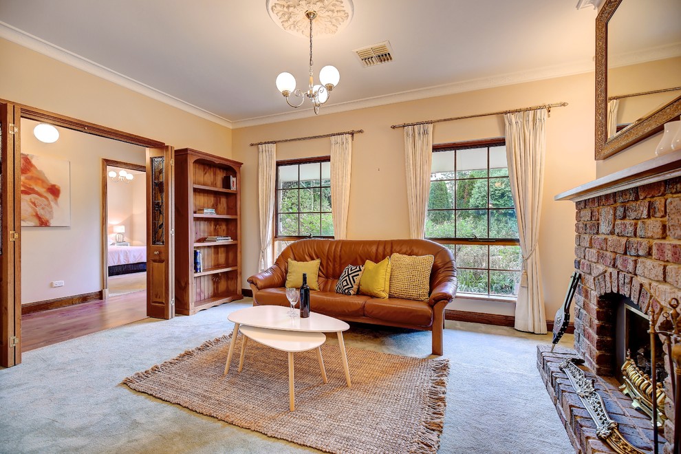 Photo of a traditional formal enclosed living room in Adelaide with yellow walls, carpet, a standard fireplace, a brick fireplace surround and no tv.
