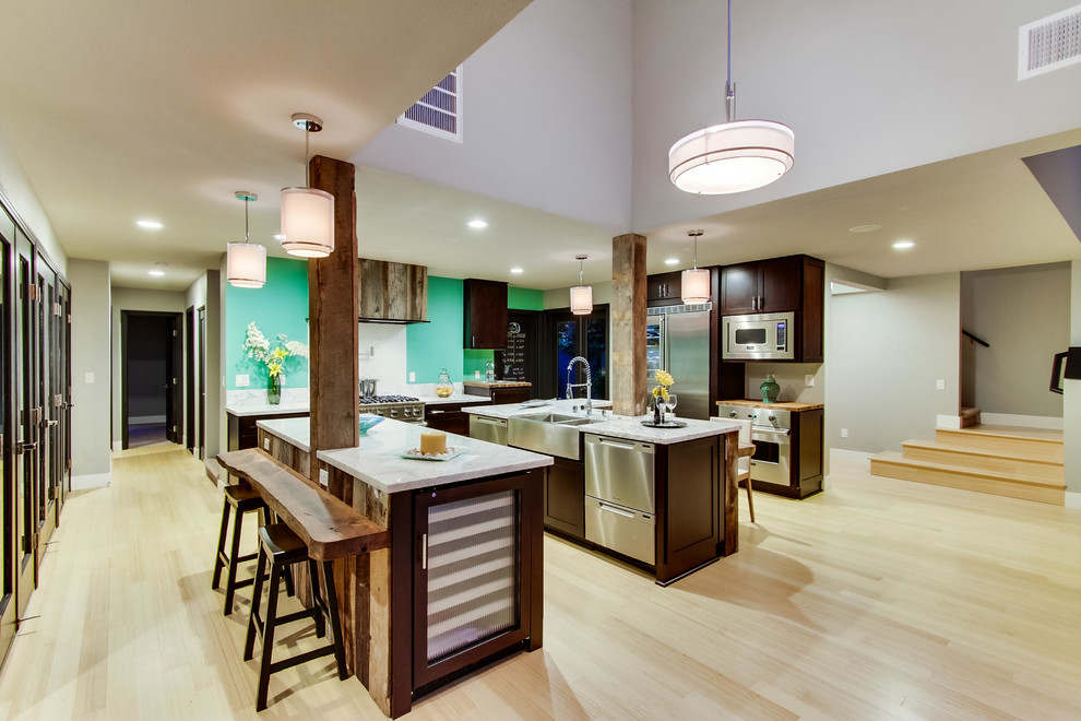 Photo of a beach style eat-in kitchen in San Diego with a farmhouse sink, recessed-panel cabinets, black cabinets, marble benchtops, green splashback, glass tile splashback and stainless steel appliances.