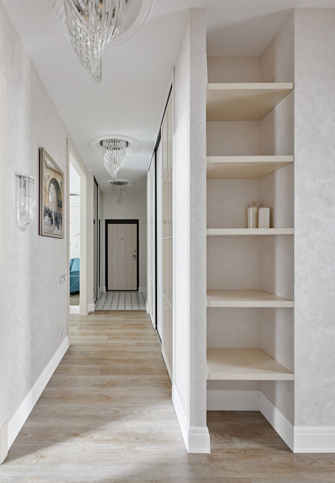 На фото: узкий коридор среднего размера в стиле неоклассика (современная классика) с бежевыми стенами, полом из керамической плитки, белым полом, многоуровневым потолком и обоями на стенах