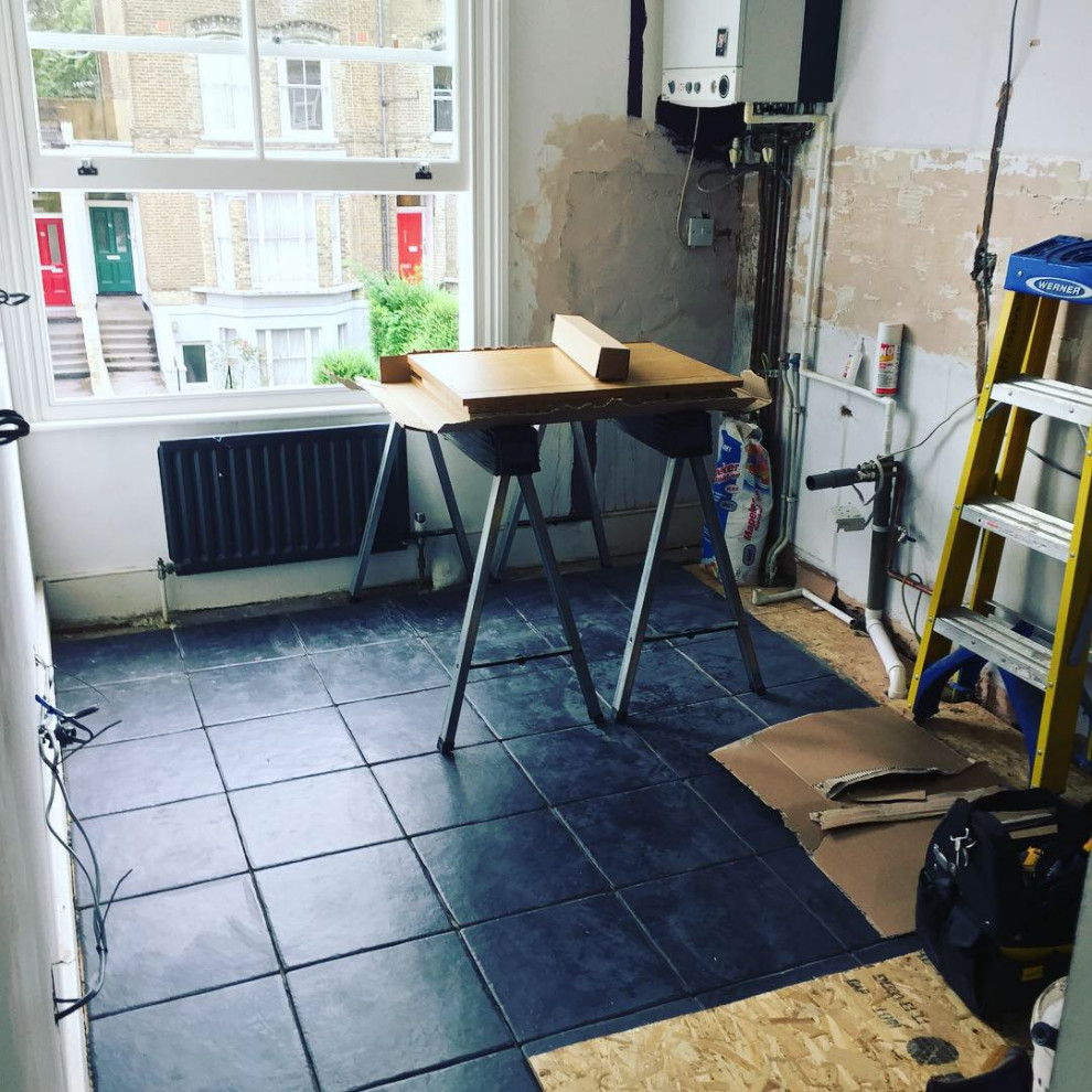 ロンドンにある高級な中くらいなヴィクトリアン調のおしゃれなキッチン (シングルシンク、シェーカースタイル扉のキャビネット、白いキャビネット、木材カウンター、白いキッチンパネル、セラミックタイルのキッチンパネル、パネルと同色の調理設備、セラミックタイルの床、黒い床、マルチカラーのキッチンカウンター) の写真