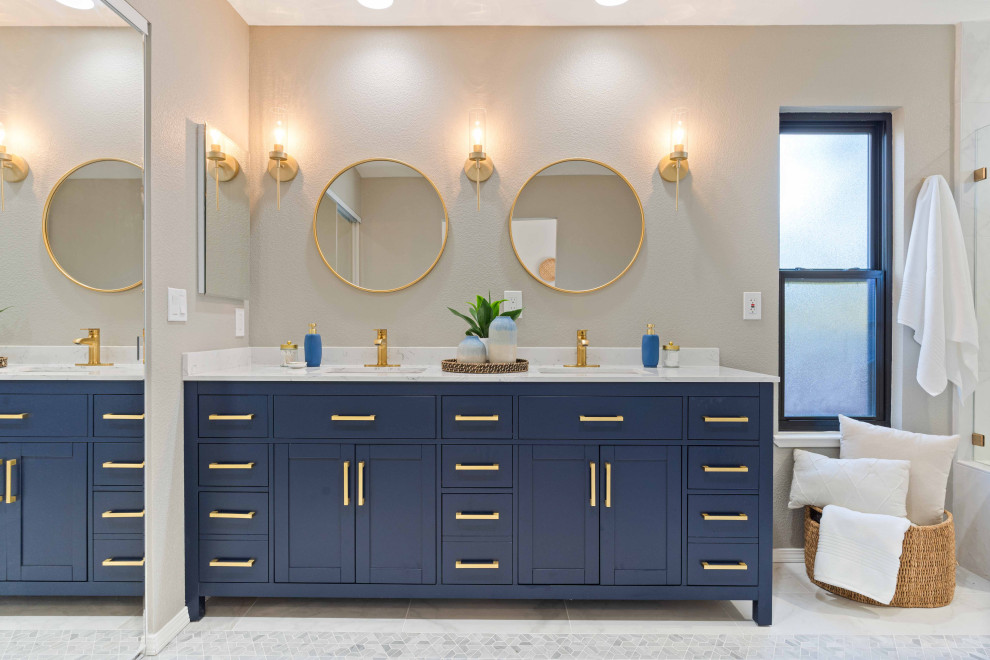 На фото: главная ванная комната среднего размера в стиле фьюжн с фасадами в стиле шейкер, синими фасадами, душем в нише, раздельным унитазом, белой плиткой, керамогранитной плиткой, серыми стенами, полом из керамогранита, врезной раковиной, столешницей из искусственного кварца, белым полом, душем с распашными дверями, белой столешницей, нишей, тумбой под две раковины и напольной тумбой с