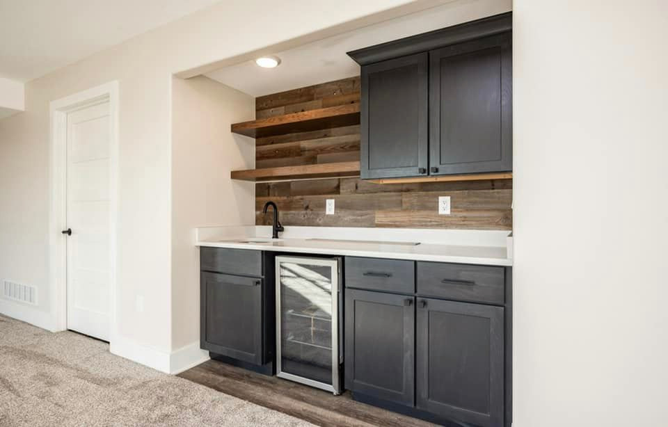 Diseño de sótano con puerta minimalista de tamaño medio con bar en casa, paredes beige, moqueta, suelo beige y machihembrado