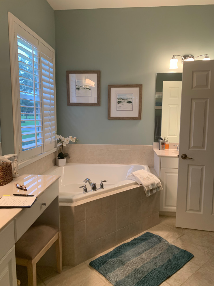 This is an example of a large beach style ensuite bathroom in Miami with raised-panel cabinets, white cabinets, a corner bath, a built-in shower, a one-piece toilet, white tiles, metro tiles, blue walls, vinyl flooring, a submerged sink, engineered stone worktops, grey floors, an open shower, white worktops, a shower bench, double sinks and a built in vanity unit.