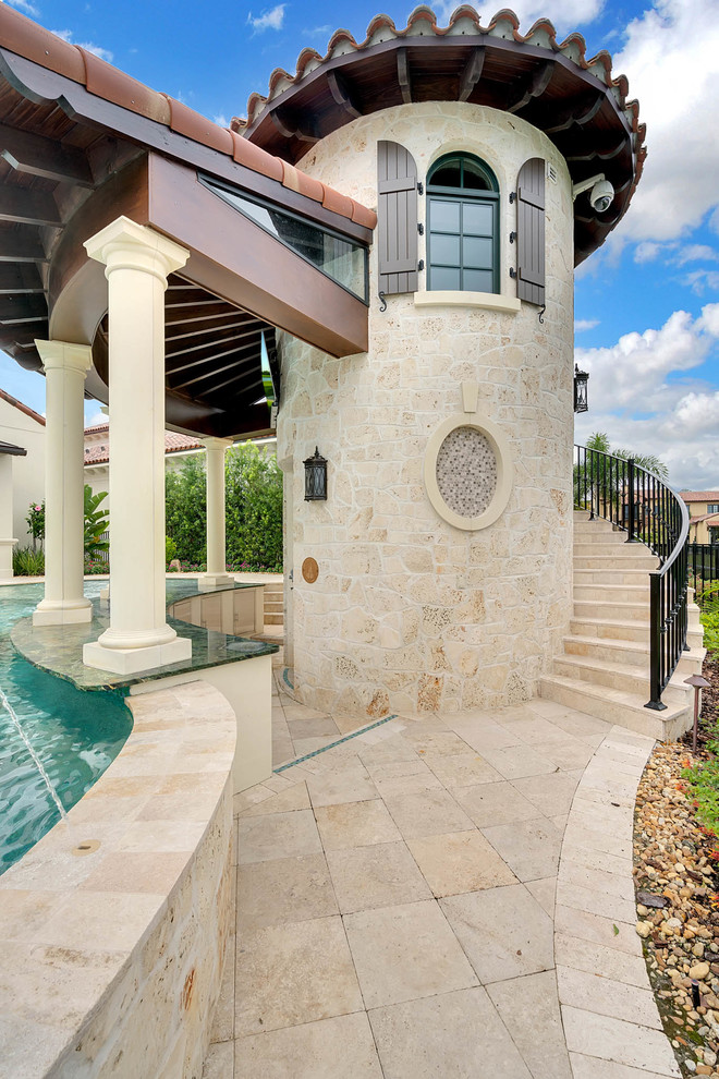 Inspiration for a large transitional backyard custom-shaped pool in Orlando with a pool house and natural stone pavers.