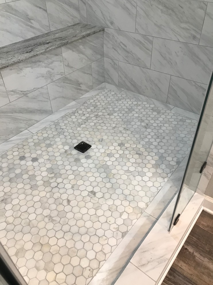 Photo of a large transitional master wet room bathroom in Houston with raised-panel cabinets, medium wood cabinets, porcelain tile, grey walls, laminate floors, an undermount sink, granite benchtops, brown floor, a hinged shower door and grey benchtops.