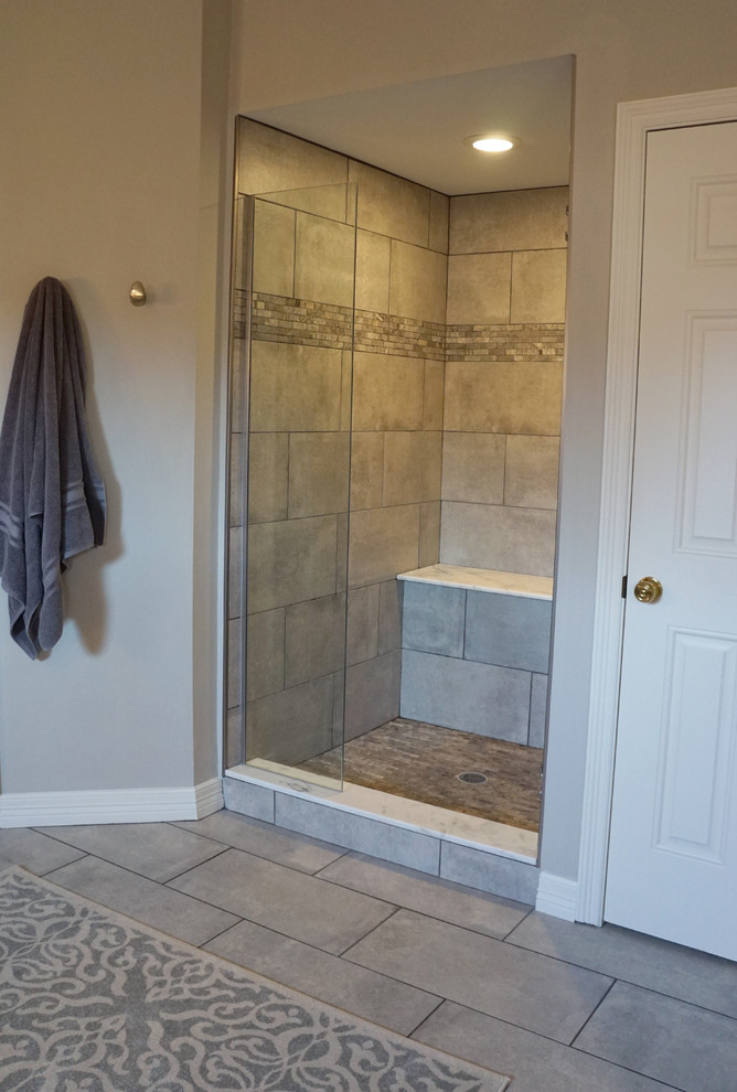 This is an example of a large transitional master wet room bathroom in Houston with raised-panel cabinets, grey cabinets, a freestanding tub, a two-piece toilet, grey walls, porcelain floors, an undermount sink, marble benchtops, grey floor, a hinged shower door, beige tile and ceramic tile.