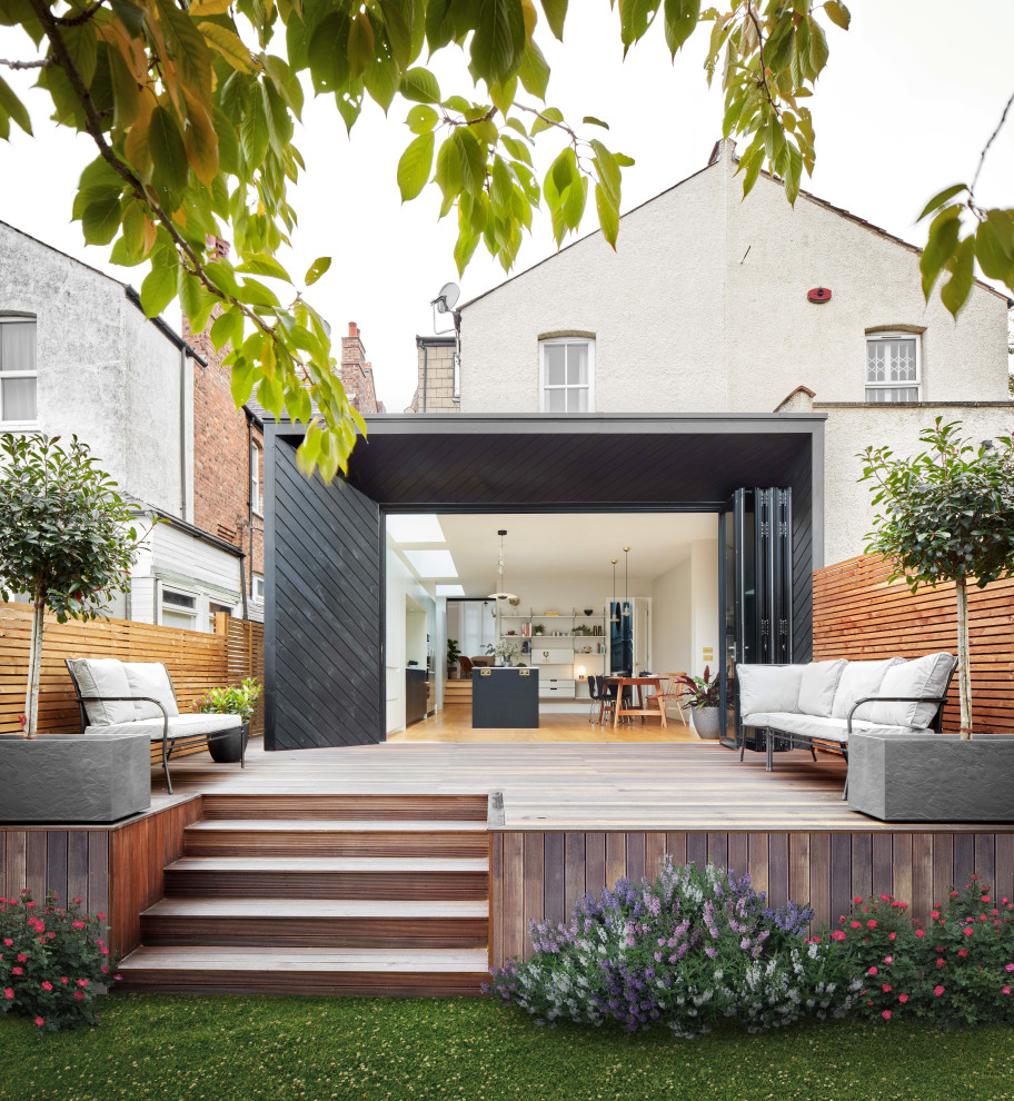 This is an example of a large contemporary back ground level wood railing terrace in London with no cover.