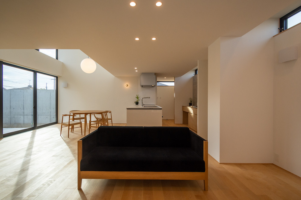 Идея дизайна: огромная открытая гостиная комната с белыми стенами, светлым паркетным полом, отдельно стоящим телевизором, потолком с обоями и обоями на стенах без камина