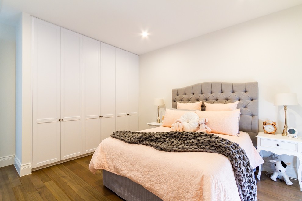 This is an example of a mid-sized traditional gender-neutral built-in wardrobe in Melbourne with shaker cabinets, white cabinets, medium hardwood floors and brown floor.