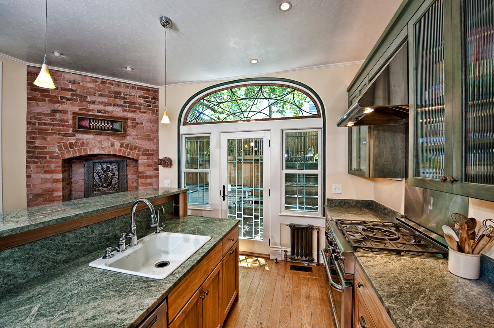 Inspiration for a small transitional l-shaped medium tone wood floor eat-in kitchen remodel in DC Metro with granite countertops, an island, a drop-in sink, glass-front cabinets, green cabinets, metallic backsplash, metal backsplash and stainless steel appliances