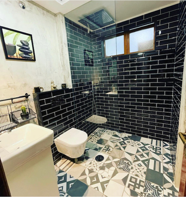 Inredning av ett modernt mellanstort vit vitt badrum med dusch, med vita skåp, en kantlös dusch, en vägghängd toalettstol, svart kakel, keramikplattor, grå väggar, cementgolv, ett undermonterad handfat och flerfärgat golv