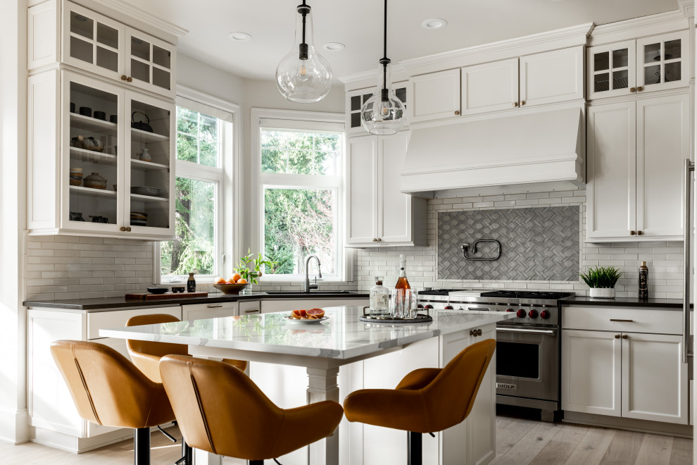 Example of a huge transitional u-shaped light wood floor and white floor eat-in kitchen design in Seattle with an undermount sink, beaded inset cabinets, white cabinets, quartzite countertops, gray backsplash, glass tile backsplash, stainless steel appliances, an island and brown countertops