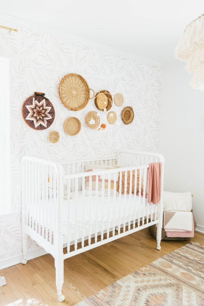 This is an example of a mid-sized country nursery for girls with white walls, light hardwood floors and brown floor.