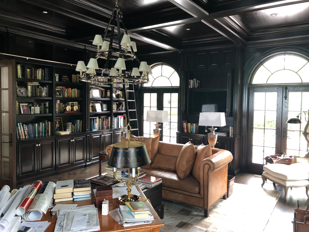 Inspiration for an expansive traditional home office in Chicago with a library, brown walls, dark hardwood floors, a standard fireplace, a wood fireplace surround, a freestanding desk and brown floor.