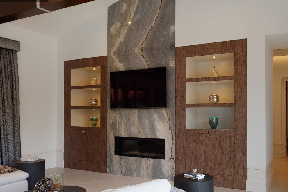 Inspiration for a large modern open concept family room in Orange County with a music area, beige walls, porcelain floors, a ribbon fireplace, a stone fireplace surround, a wall-mounted tv, beige floor and exposed beam.