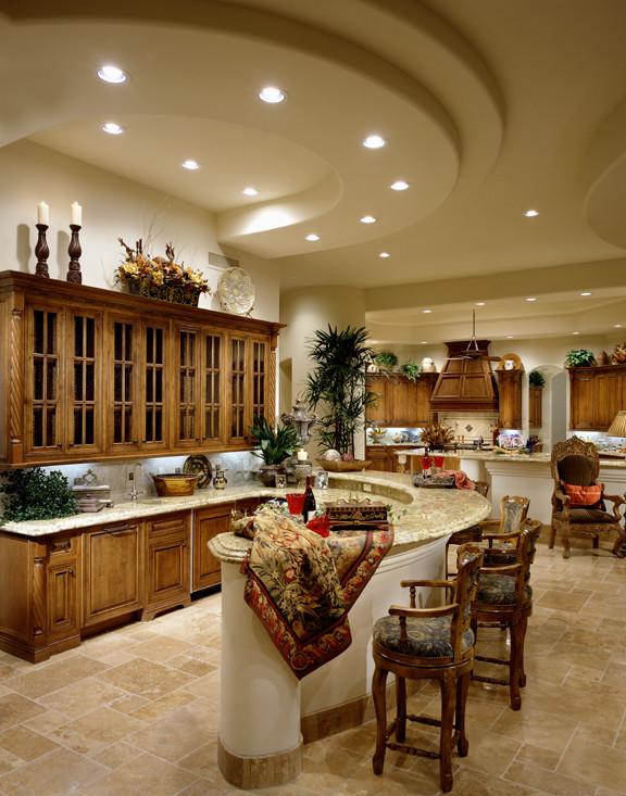 Expansive traditional galley seated home bar in Phoenix with recessed-panel cabinets, granite benchtops, white splashback, stone tile splashback, travertine floors and medium wood cabinets.