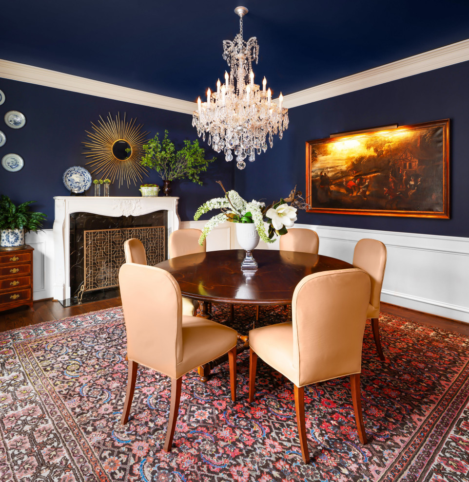 Klassisches Esszimmer mit blauer Wandfarbe, dunklem Holzboden, Kamin, braunem Boden und vertäfelten Wänden in Dallas