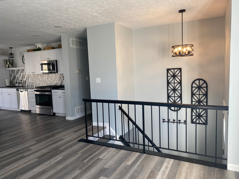 Example of a large transitional l-shaped vinyl floor and gray floor open concept kitchen design in Cincinnati with an undermount sink, raised-panel cabinets, white cabinets, granite countertops, multicolored backsplash, ceramic backsplash, stainless steel appliances, an island and black countertops
