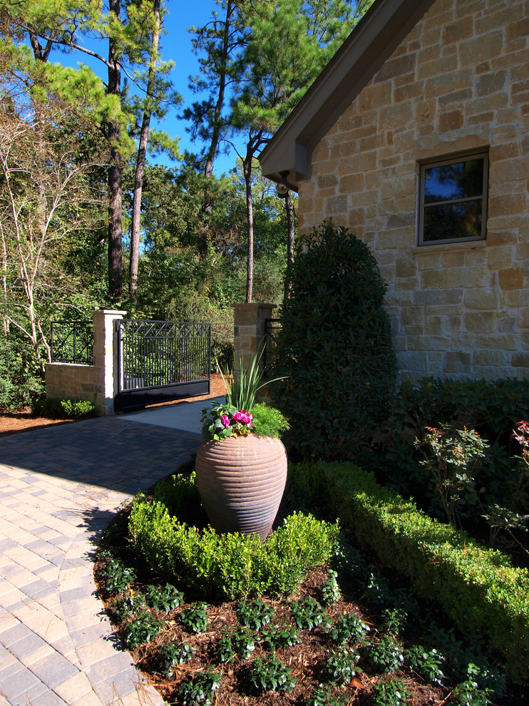 Photo of a mid-sized traditional front yard partial sun driveway in Houston with a container garden and brick pavers.