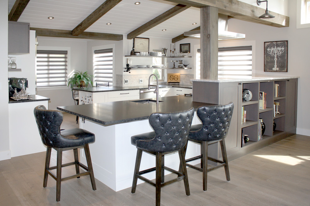 Open concept kitchen - mid-sized rustic u-shaped medium tone wood floor open concept kitchen idea in Vancouver with an undermount sink, shaker cabinets, white cabinets, granite countertops, gray backsplash, stone tile backsplash, stainless steel appliances and a peninsula