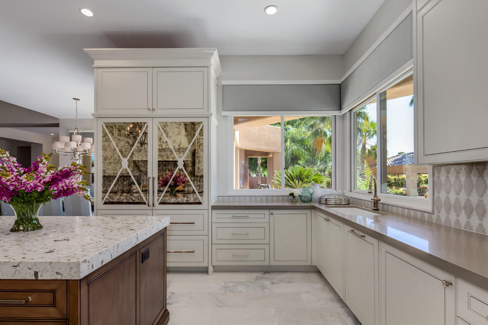 Example of a large transitional l-shaped marble floor and white floor eat-in kitchen design in Phoenix with a drop-in sink, shaker cabinets, white cabinets, granite countertops, beige backsplash, ceramic backsplash, stainless steel appliances and two islands