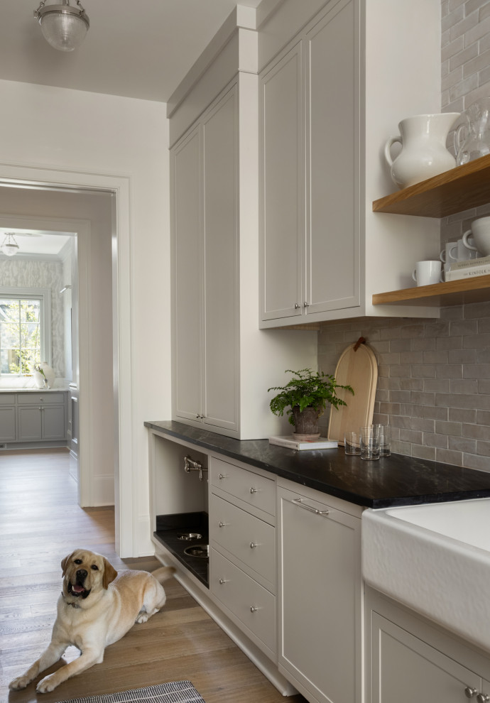 This is an example of a mid-sized transitional galley kitchen pantry in DC Metro with beige cabinets, beige splashback, stainless steel appliances, light hardwood floors and brown floor.