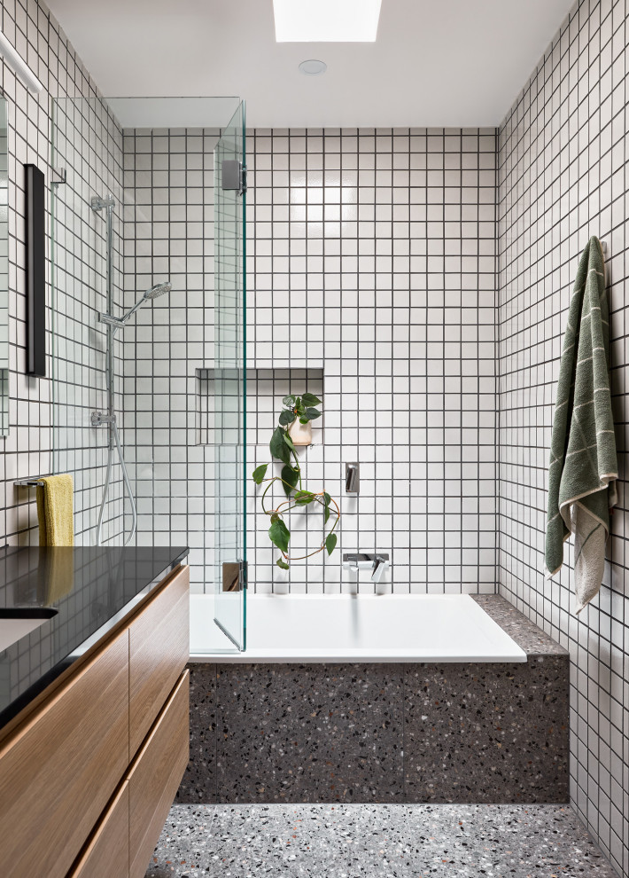 Esempio di una piccola stanza da bagno design con ante lisce, ante in legno chiaro, vasca ad alcova, piastrelle bianche, top in superficie solida, top nero, un lavabo e mobile bagno sospeso