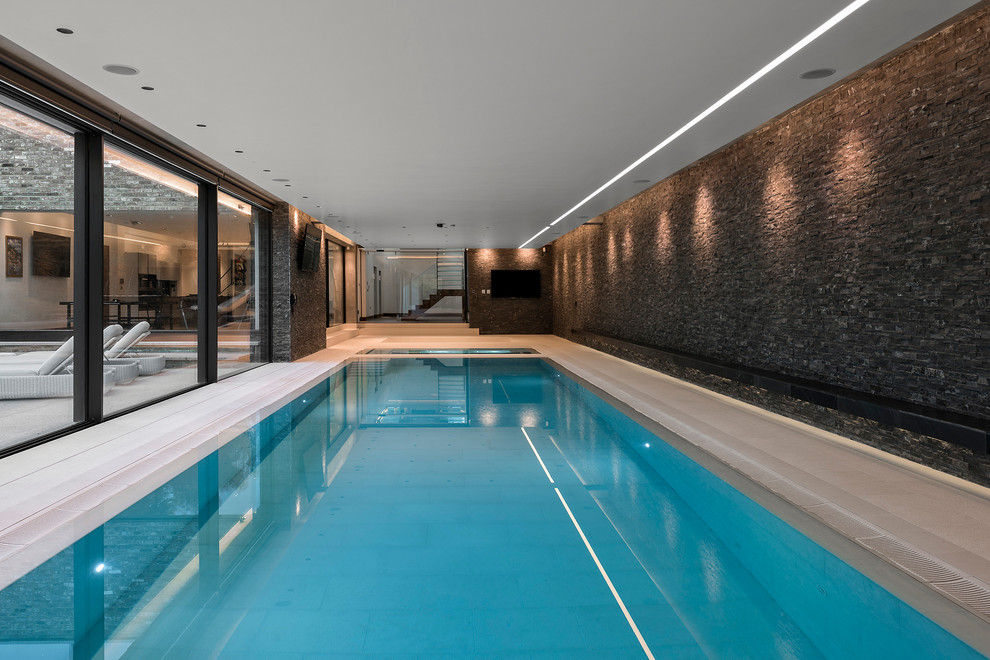 This is an example of an expansive contemporary indoor rectangular pool in Hampshire with a hot tub.