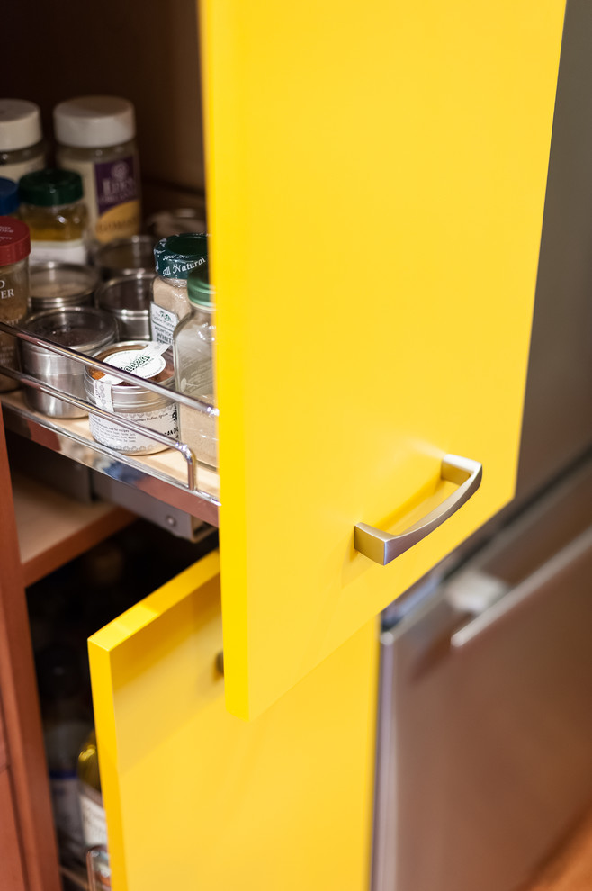 Inspiration for a small eclectic galley kitchen pantry in Portland with an undermount sink, flat-panel cabinets, yellow cabinets, granite benchtops, multi-coloured splashback, ceramic splashback, stainless steel appliances, medium hardwood floors and no island.