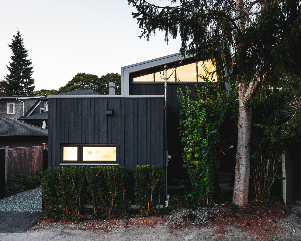 Réalisation d'une façade de maison noire nordique en bois de taille moyenne et de plain-pied.