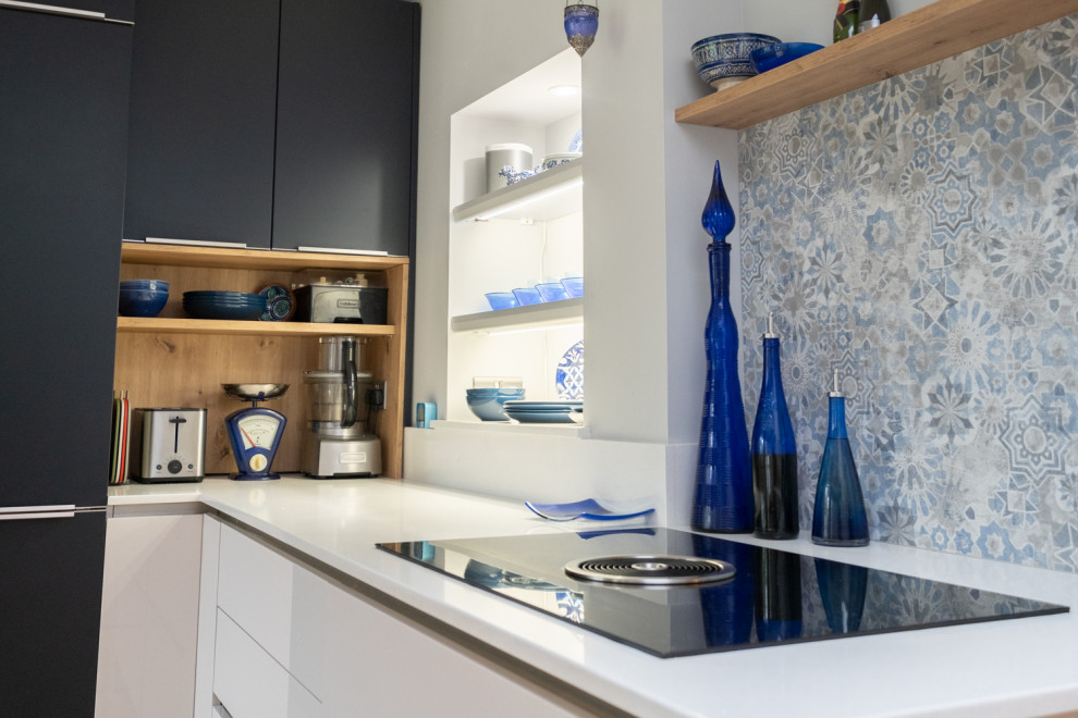 Esempio di una cucina minimalista di medie dimensioni con lavello a vasca singola, ante lisce, top in quarzite, paraspruzzi blu, elettrodomestici neri, pavimento in legno massello medio, nessuna isola e top bianco