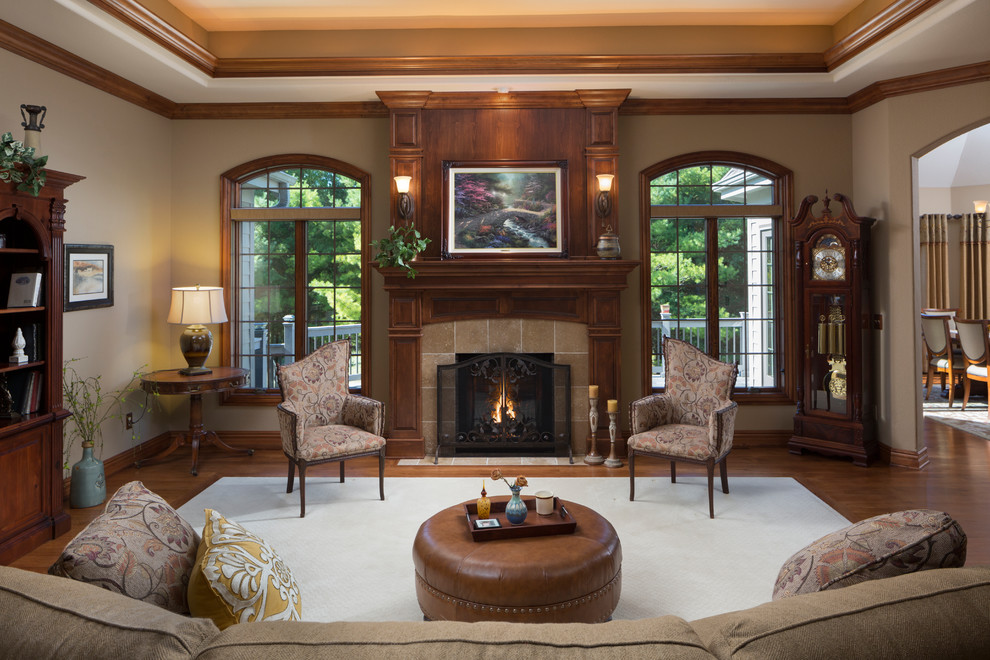 Photo of a traditional formal enclosed living room in Milwaukee with beige walls, dark hardwood floors, a standard fireplace, a tile fireplace surround, no tv and brown floor.