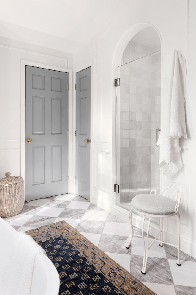 Freestanding bathtub - large transitional master white tile and ceramic tile porcelain tile, white floor, double-sink, vaulted ceiling and wall paneling freestanding bathtub idea with shaker cabinets, light wood cabinets, a one-piece toilet, white walls, an undermount sink, quartz countertops, a hinged shower door, black countertops, a niche and a built-in vanity