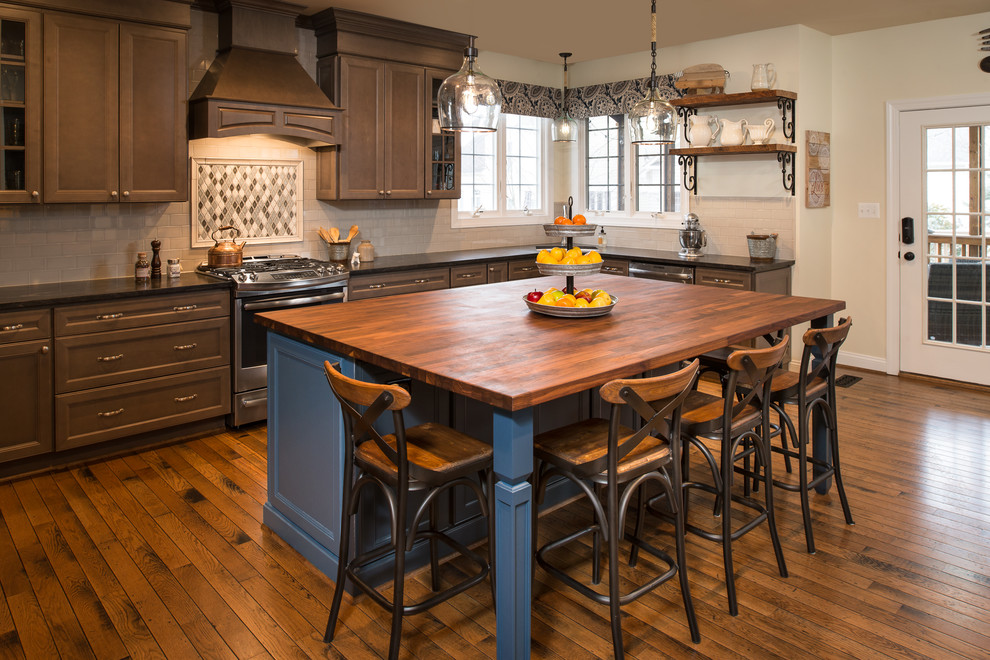 Inspiration for a mid-sized traditional l-shaped kitchen in DC Metro with recessed-panel cabinets, wood benchtops, stainless steel appliances, with island, brown floor, dark wood cabinets, multi-coloured splashback, mosaic tile splashback and dark hardwood floors.