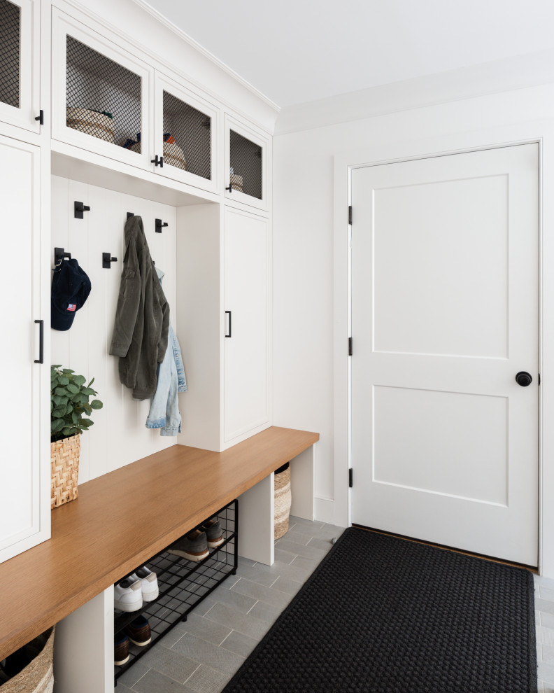 Transitional mudroom in New York with white walls and planked wall panelling.