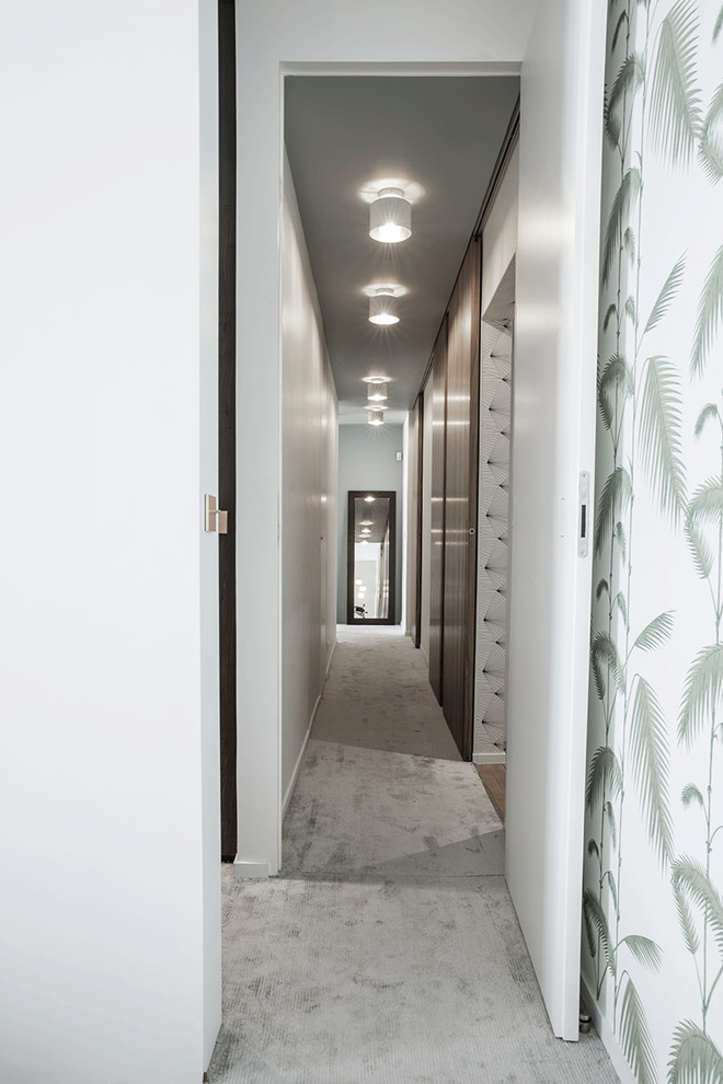 Large contemporary hallway in Paris with white walls, carpet and beige floor.