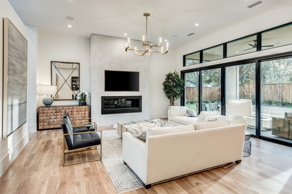 Inspiration for a modern open concept living room in Dallas with white walls, light hardwood floors, a standard fireplace, a plaster fireplace surround, a wall-mounted tv and brown floor.