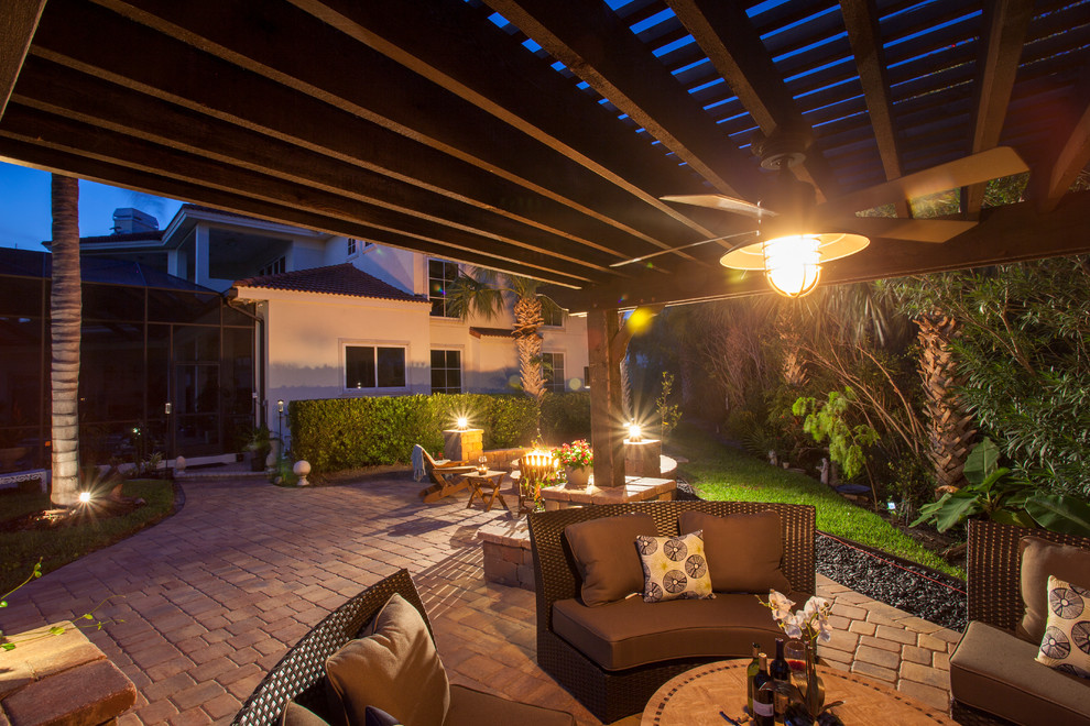Design ideas for an expansive traditional backyard patio in Jacksonville with a fire feature, natural stone pavers and a pergola.