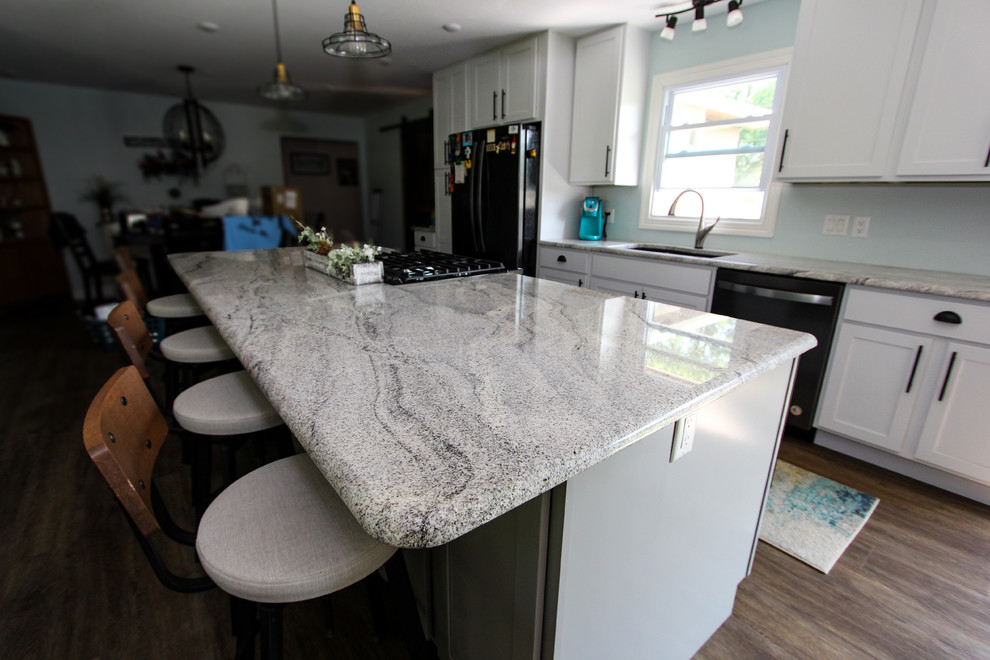 Example of a mid-sized transitional single-wall laminate floor and brown floor open concept kitchen design in Minneapolis with an undermount sink, shaker cabinets, gray cabinets, granite countertops, stainless steel appliances, an island and gray countertops